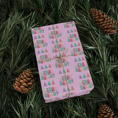 a present wrapped in a pink wrapping paper surrounded by pine cones