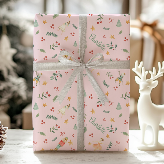 a pink gift box with a bow on a table next to a christmas tree