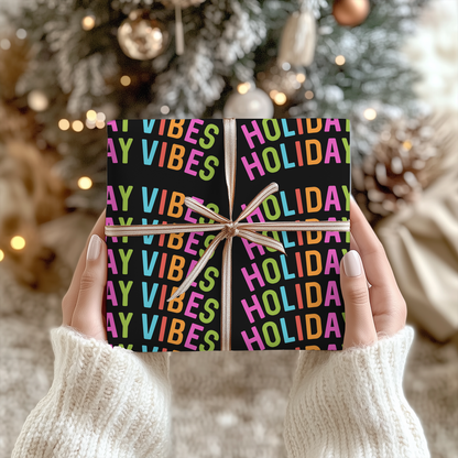 a person holding up a holiday gift in front of a christmas tree
