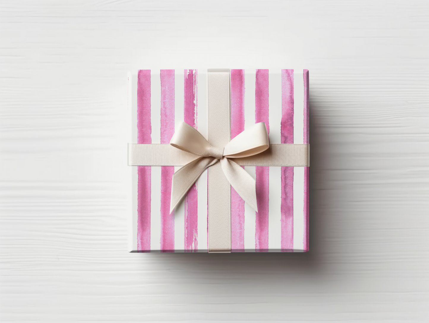 a pink and white striped gift box with a bow