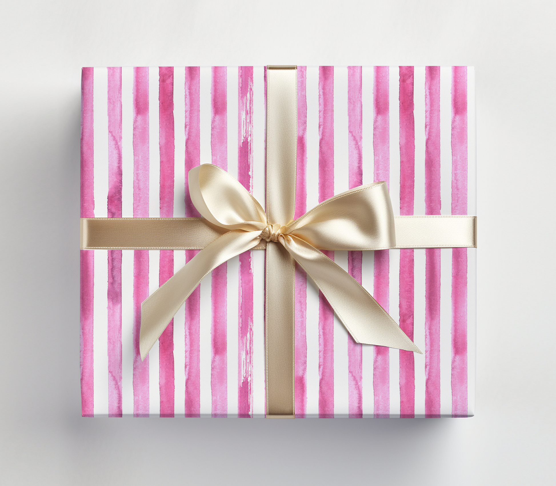 a pink and white striped gift box with a gold bow